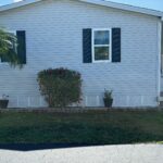 White brick house exterior with a window and plants in front.
